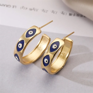 Macro shot of gold-plated C-shaped earrings with blue and white enamel evil eye patterns
