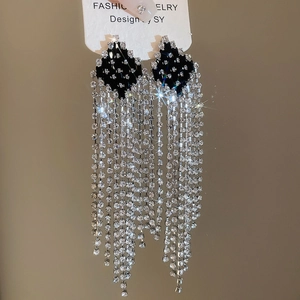 Detail view of black rhombic stud earrings with sparkling silver rhinestone tassels