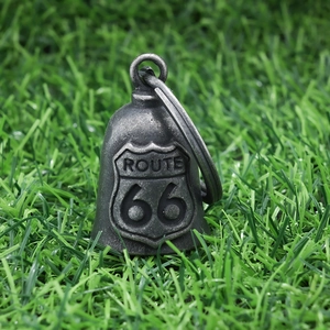 Detail of vintage silver Route 66 motorcycle bell charm on a green grass background