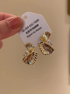 Macro detail of gold-plated twisted fan stud earrings with sparkling cubic zirconia stones