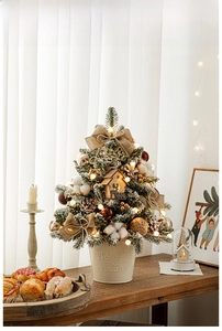 Mini snowy Christmas tree with LED lights and decorations in a vintage metal bucket