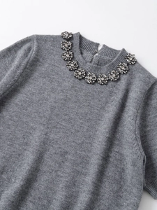 Detail of round neckline with floral rhinestones and teardrop back opening on grey knit top