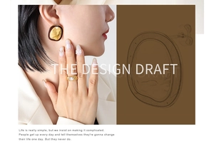Detail view of gold textured earrings with dark border and matching large gemstone ring
