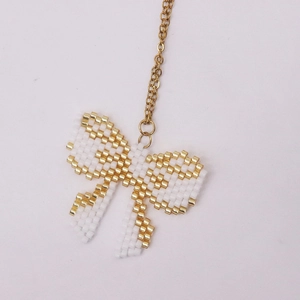 Detail of handcrafted MIYUKI seed bead bow pendant with golden chain and white beads