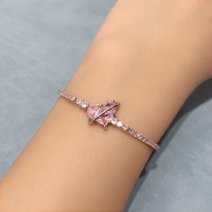 Close-up of pink heart zircon bracelet with silver planet ring design and crystal accents