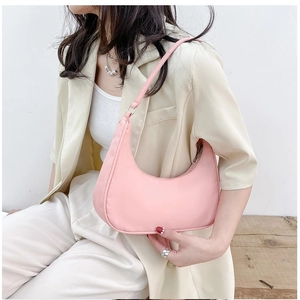 Model wearing pink nylon crescent shoulder bag against a minimalist studio background