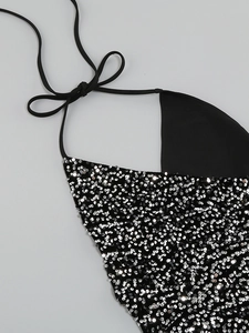Detailed view of shimmering silver sequins and halter neck tie on a black party dress