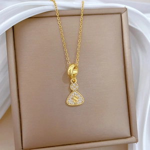 Macro detail of gold-plated S-letter gourd pendant with crystals on velvet
