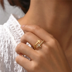 Detail of gold-plated cross ring with sparkling crystals worn on finger
