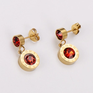 Detailed macro view of gold-tone earrings with red stones and Roman numeral engraving