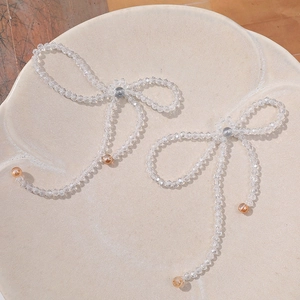 Detail of beaded crystal bow earrings with amber accents on a textured tray