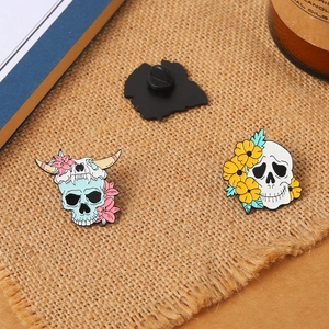 Detailed close-up of enamel skull and floral brooches with butterfly clasp back