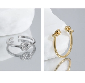 Detailed view of silver and gold knotted S925 rings showing the smooth metal texture