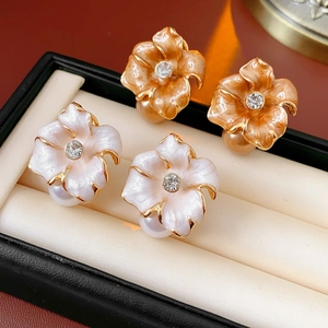 Détail de boucles d'oreilles fleurs vintage avec perles et strass en orange et blanc