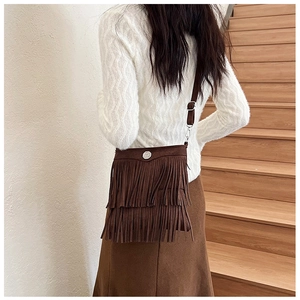 Lifestyle shot of model wearing a brown suede fringe crossbody bag with adjustable strap