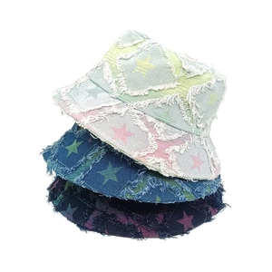 Three colors of washed denim bucket hats with star prints and frayed edges in detail view