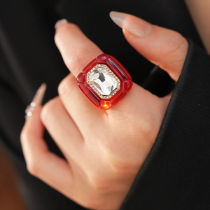 Détail d'une bague vintage en résine avec un grand cristal carré rouge serti de strass