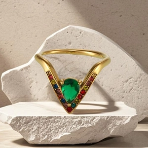Détail de la bague en V dorée avec pierre verte et zircons colorés sertis de côté
