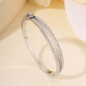 Detailed close-up of a silver stainless steel bangle with geometric hollows and crystals