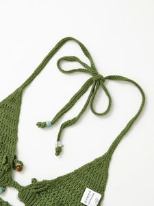 Detail of green handmade crochet top with intricate knit patterns and decorative beads