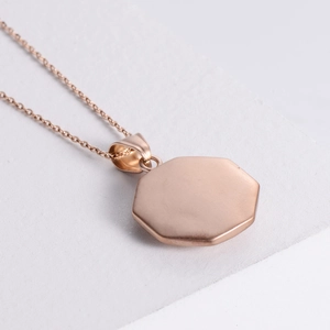 Minimalist rose gold octagon tai chi pendant necklace on a textured stone surface