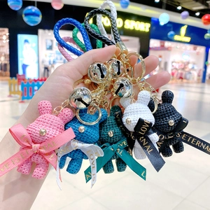Five assorted colors of woven resin bear keychains with gold bells and leather wrist straps