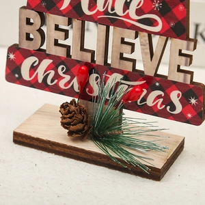 Dettaglio di un addobbo natalizio in legno con scritta Believe e decorazione pigna