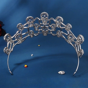 Silver rhinestone skull crown tiara for Halloween party costume on blue fabric background