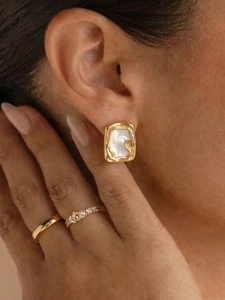 Nahaufnahme von Luxus-Goldohrsteckern mit Perlmutt und passenden Ringen für Damen