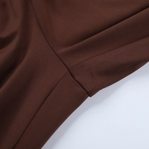 Close-up of double-stitched seams on dark brown slim-fit jumpsuit fabric