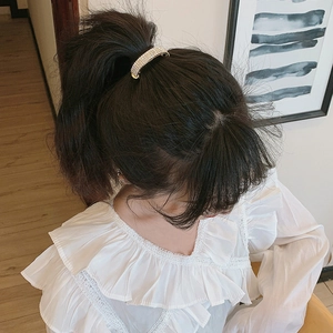 Elegant gold rhinestone ponytail hair clip worn by a model in a natural setting