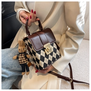 Detail of French style quilted crossbody bag featuring a golden twist lock and bunny charm
