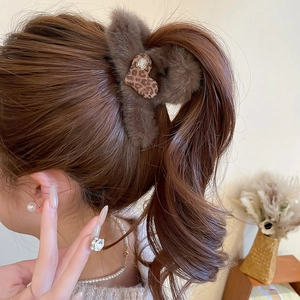 Detail view of brown plush heart hair claw with leopard print and rhinestone on hair