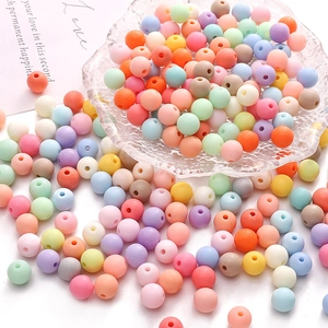 Colorful 8-16mm matte acrylic beads scattered on white surface with a glass bowl