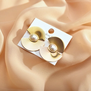 Close-up of golden petal earrings with central pearl on elegant silk background