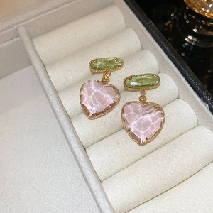 Gros plan sur des boucles d'oreilles cœur vintage avec cristaux verts et roses