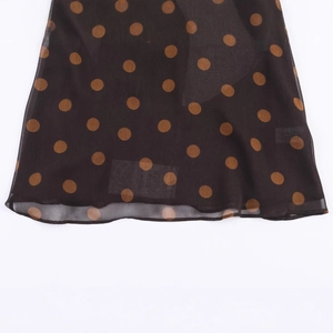 Close-up of brown polka dot chiffon top hem with delicate ruffled edge detail