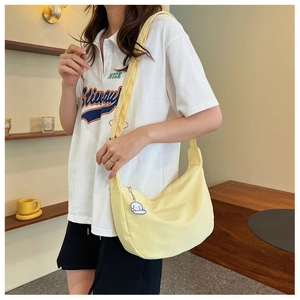 Detail of light yellow crescent canvas bag with a cute white cloud charm accessory