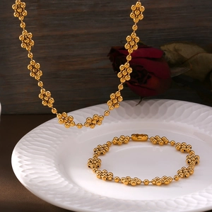Elegant gold beaded floral necklace and bracelet set on a vintage ceramic plate