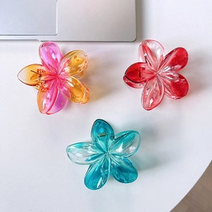 Detailed close-up of translucent gradient plumeria flower hair claws in three colors