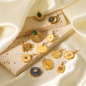 Detail of vintage gold celestial charms with colorful enamel on beige stone surface