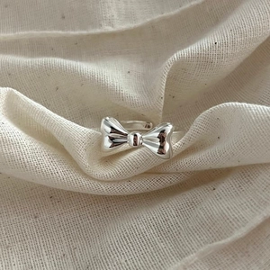 Minimalist 925 sterling silver bow ring with an adjustable open design on linen fabric