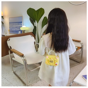 Detailed view of child model wearing a yellow quilted mini bag with pearl handle and chain