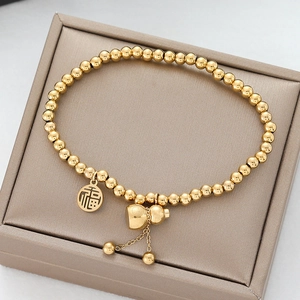 Detail of gold beaded bracelet featuring Fu character charm and small gourd pendant
