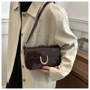 Detail of glossy dark brown patent leather and golden U-shaped metal buckle on the bag