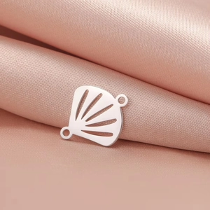 Detail of 304 stainless steel lotus shell charm on soft pink silk fabric background