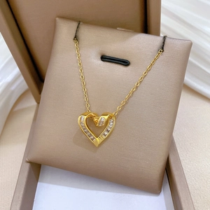 Elegant gold heart pendant necklace with clear zircons displayed in a beige jewelry box