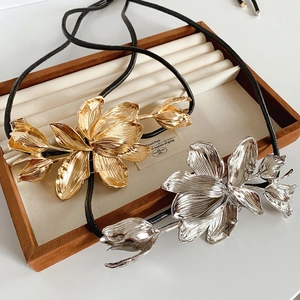 Detail of large metal tulip flower pendants in gold and silver on black leather cords