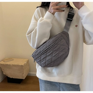 Lifestyle shot of grey quilted crossbody chest bag worn over a white sweatshirt
