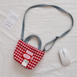 Detailed view of red plaid tote bag with cherry patch and denim blue strap details